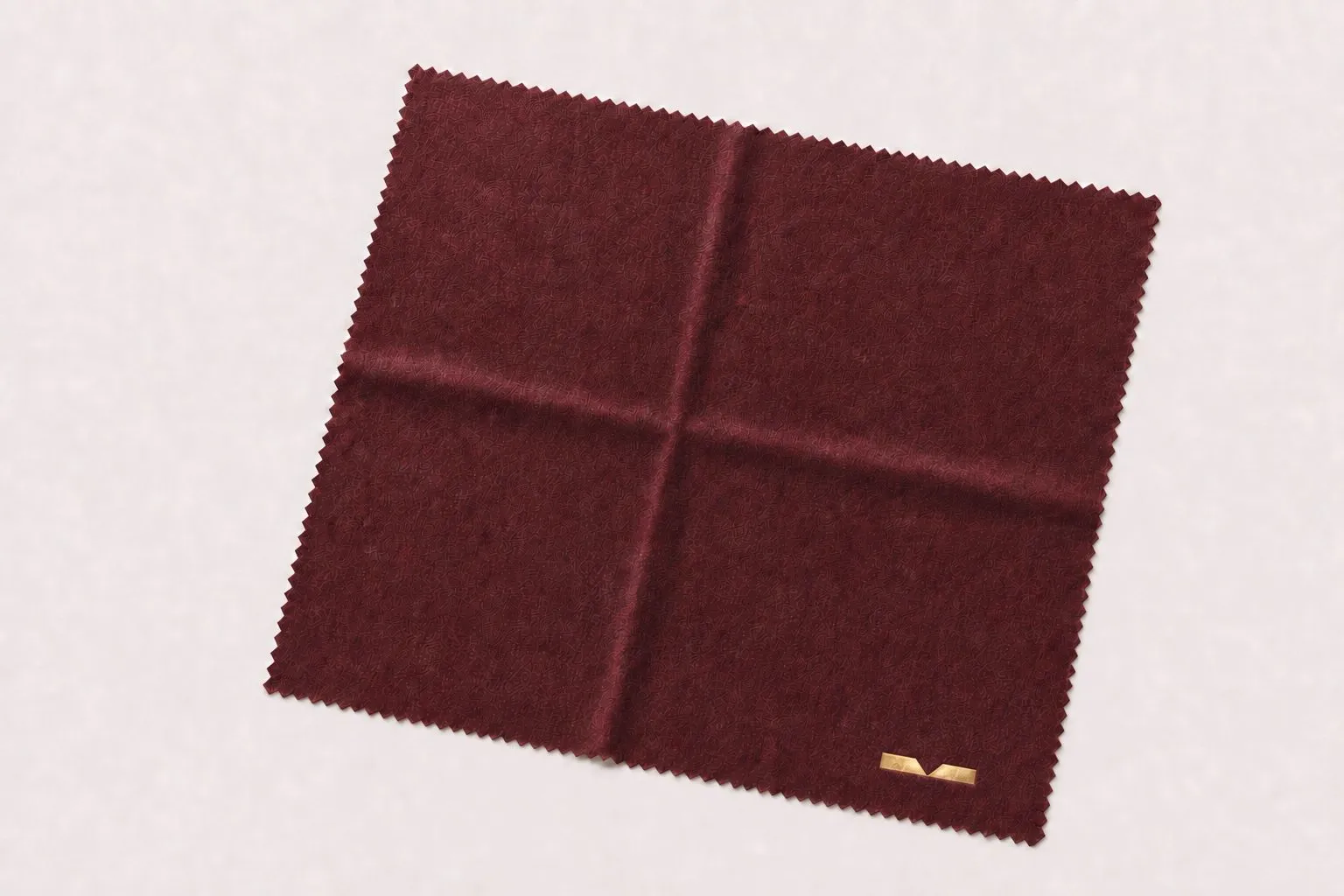 Oxblood microfibre cloth with embossed mark.