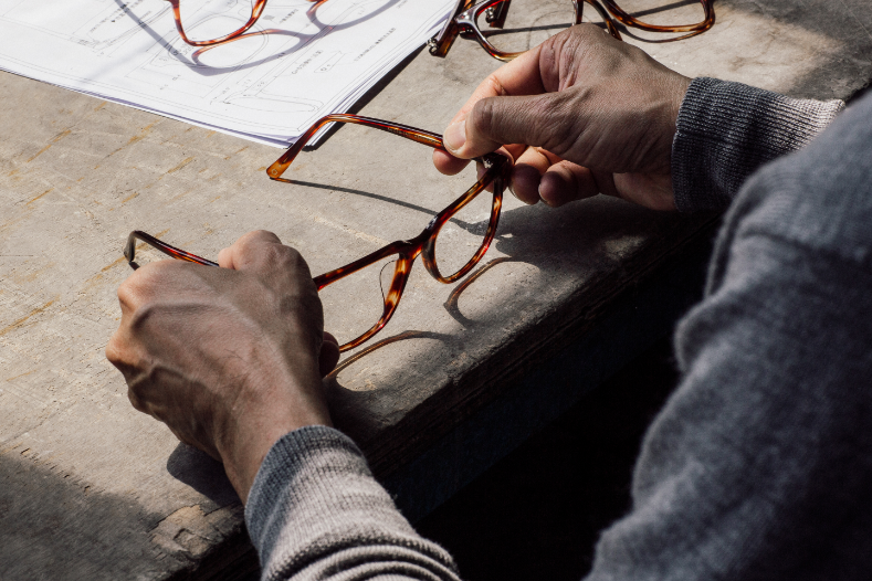 Hands inspecting a tortoise acetate frame.